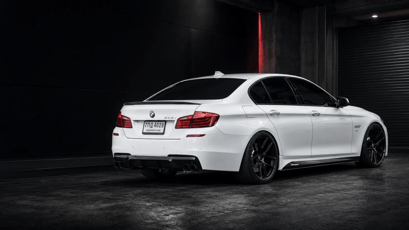 White performance sedan fitted with CORVEN forged wheels in a dark automotive workshop